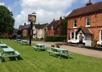 a group of picnic tables on the grass in front of a building at Idyllic rural retreat, easy access to Cambridge