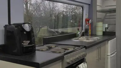 a kitchen with a stove and a sink and a window at The Carriage Ely in Coveney