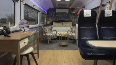 a train room with a bed and a desk and chairs at The Carriage Ely in Coveney