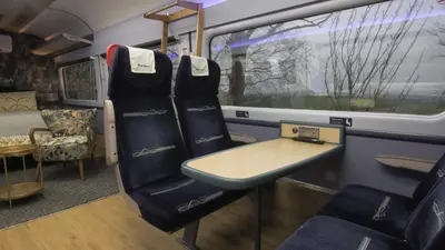 a train car with a table in the middle at The Carriage Ely in Coveney
