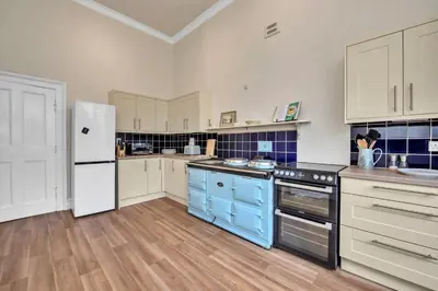 a kitchen with blue cabinets and a white refrigerator at Finest Retreats - Clavering Hall in Saffron Walden