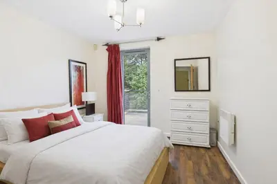 a white bedroom with a bed and a window at Station Apartment in Cambridge