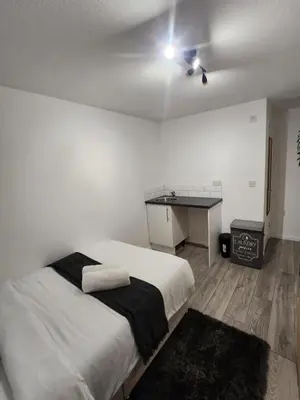 a white bedroom with a bed and a desk at Ensuite premier rooms in Basildon