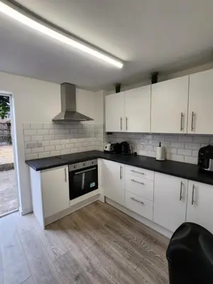 a kitchen with white cabinets and a stove top oven at Ensuite premier rooms in Basildon