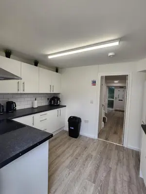 a kitchen with white cabinets and a wooden floor at Ensuite premier rooms in Basildon