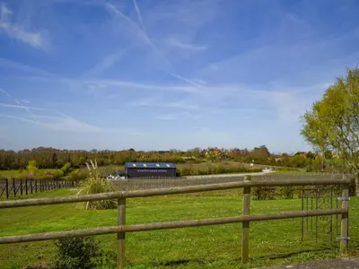 a wooden fence in a field with a barn at Ivy No1 - Uk49251 in Althorne