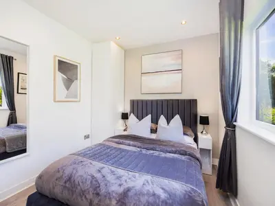 a bedroom with a large bed and two windows at Essex Barn House - Uk48354 in Romford