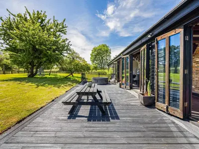 a wooden deck with benches and a building at Essex Barn House - Uk48354 in Romford