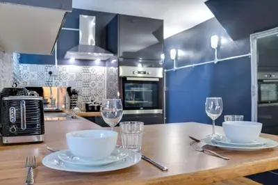 a kitchen with a wooden table with plates and wine glasses at Studio Apartment with Private Garden in Southend-on-Sea