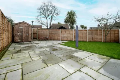 a patio in a backyard with a wooden fence at 21 Urban Road, sleeps 5 guests, Leiston, near Sizewell, Managed by Aldeburgh Coastal Cottages in Leiston