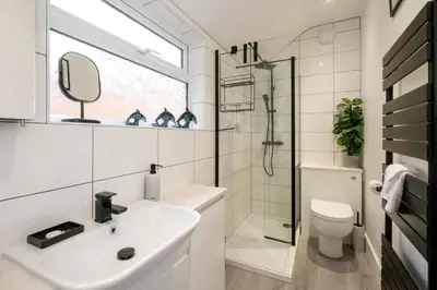 a white bathroom with a sink and a shower at 21 Urban Road, sleeps 5 guests, Leiston, near Sizewell, Managed by Aldeburgh Coastal Cottages in Leiston