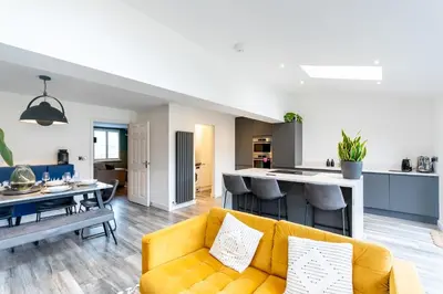 a living room with a yellow couch and a kitchen at Comfortable 3 bedroom Home Chelmsford Sleeps 5 - Pass the Keys in Chelmsford