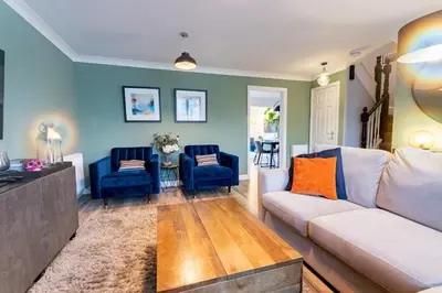a living room with a couch and two blue chairs at Comfortable 3 bedroom Home Chelmsford Sleeps 5 - Pass the Keys in Chelmsford
