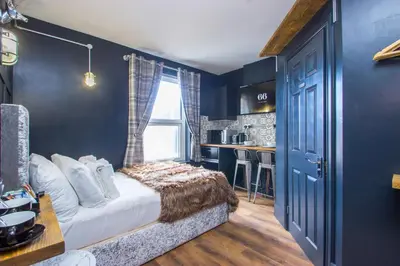 a bedroom with blue walls and a bed and a kitchen at Cozy Studio Apartment in Southend-on-Sea in Southend-on-Sea