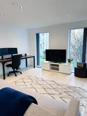 a living room with a flat screen tv and a desk at Bright Corner Apartment by Cambridge Station with Free Allocated Underground Parking & Flexible Beds in Cambridge