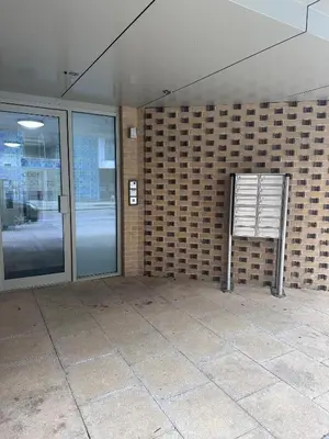 a building with a sign next to a brick wall at Bright Corner Apartment by Cambridge Station with Free Allocated Underground Parking & Flexible Beds in Cambridge