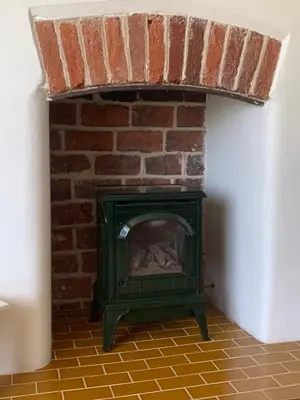 a green fireplace in a room with a brick wall at Dog-friendly rural retreat in Bury Saint Edmunds