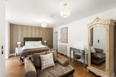 a bedroom with a bed and a couch and a mirror at Modern 3BR Basement Flat with Outdoor Terrace in Southend-on-Sea