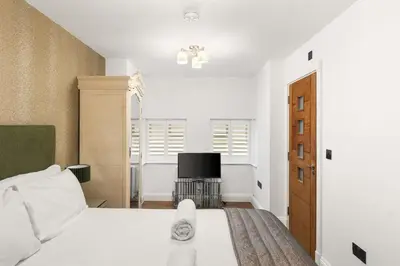a bedroom with a white bed and a television at Modern 3BR Basement Flat with Outdoor Terrace in Southend-on-Sea