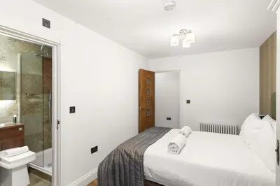 a white bedroom with a bed and a shower at Modern 3BR Basement Flat with Outdoor Terrace in Southend-on-Sea
