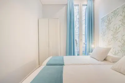 a bedroom with a bed with blue curtains and a window at Apartment Clarke in Cambridge
