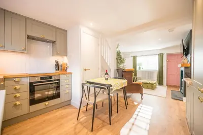 a kitchen with a table and a dining room at Pink Cottage, Leiston in Leiston