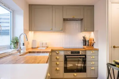 a kitchen with green cabinets and a sink at Pink Cottage, Leiston in Leiston