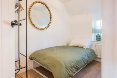 a bedroom with a bed and a mirror on the wall at Pink Cottage, Leiston in Leiston