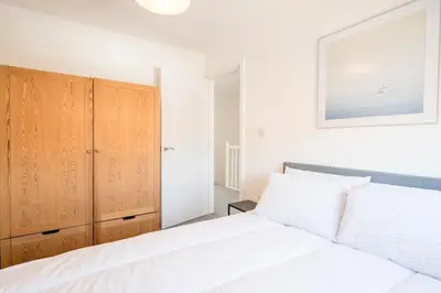 a bedroom with a white bed and a wooden cabinet at Modern 2-Bed Home in Leiston in Leiston