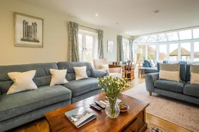 a living room with a couch and a table at Hermitage House, Thorpeness - sleeps 12 - Large Thorpeness house on the banks of Thorpness Meare - a boating lake - Close to Thorpeness beach, Golf Club and Thorpeness Country Club - Aldeburgh Coastal Cottages in Thorpeness