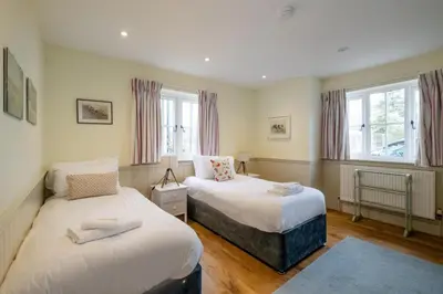 a bedroom with two beds and two windows at Hermitage House, Thorpeness - sleeps 12 - Large Thorpeness house on the banks of Thorpness Meare - a boating lake - Close to Thorpeness beach, Golf Club and Thorpeness Country Club - Aldeburgh Coastal Cottages in Thorpeness