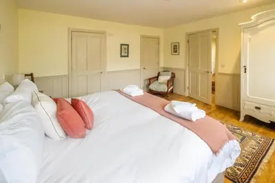 a bedroom with a large white bed with red pillows at Hermitage House, Thorpeness - sleeps 12 - Large Thorpeness house on the banks of Thorpness Meare - a boating lake - Close to Thorpeness beach, Golf Club and Thorpeness Country Club - Aldeburgh Coastal Cottages in Thorpeness