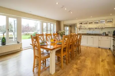 a dining room with a table and chairs and a kitchen at Hermitage House, Thorpeness - sleeps 12 - Large Thorpeness house on the banks of Thorpness Meare - a boating lake - Close to Thorpeness beach, Golf Club and Thorpeness Country Club - Aldeburgh Coastal Cottages in Thorpeness