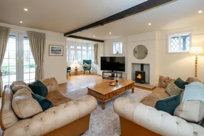 a living room with two couches and a tv at Heronsmead, sleeps 8 - Large Thorpeness house on the banks of Thorpness Meare - a boating lake - Close to Thorpeness beach, Golf Club and Thorpeness Country Club - Aldeburgh Coastal Cottages in Thorpeness