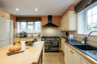 a kitchen with a counter with a sink and a stove at Heronsmead, sleeps 8 - Large Thorpeness house on the banks of Thorpness Meare - a boating lake - Close to Thorpeness beach, Golf Club and Thorpeness Country Club - Aldeburgh Coastal Cottages in Thorpeness