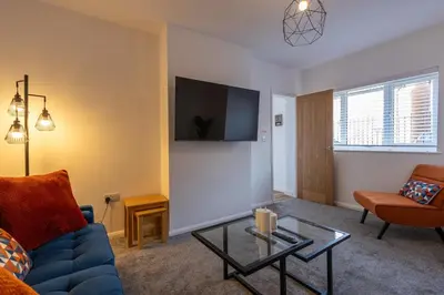a living room with a blue couch and a tv at Sizewell - Contractor Accommodation in Leiston