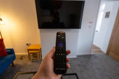a person holding a remote control in a living room at Sizewell - Contractor Accommodation in Leiston