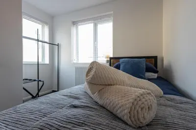 a bed with a pillow on it with two windows at Sizewell - Contractor Accommodation in Leiston