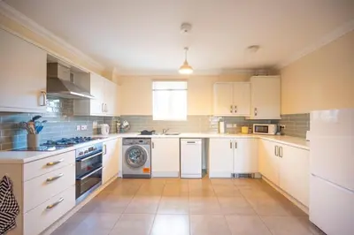 a large kitchen with white cabinets and a dishwasher at Comfortable 2-Bedroom Home in Framlingham in Framlingham