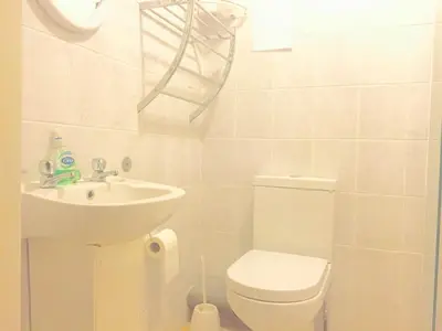 a white bathroom with a toilet and a sink at Southend Inn Hotel - Close to Beach, Train Station & Southend Airport in Southend-on-Sea
