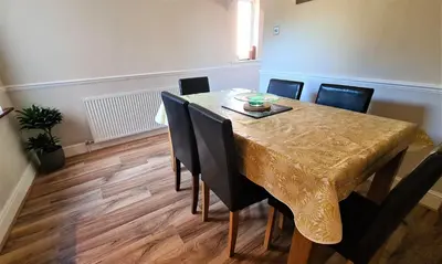 a dining room table with chairs and a gold tablecloth on it at Castle Cottage in Rayleigh