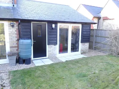 a house with a black door and a yard at Old School House Studio in Stetchworth