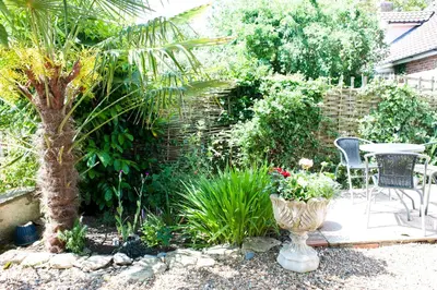 a garden with a table and chairs and plants at Little Chequers in Friston