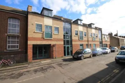 a brick building with cars parked in a parking lot at Citystay Living - Dove House in Cambridge