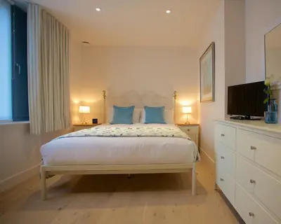 a bedroom with a bed with blue pillows and a television at Citystay Living - Pringle House in Cambridge