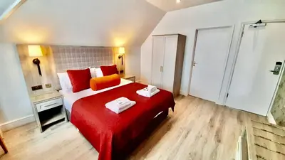 a bedroom with a red bed with towels on it at Hotel Coco in Felixstowe
