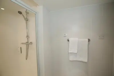 a bathroom with a shower and a white towel at Ramada Cambridge in Cambridge