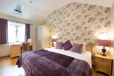 a bedroom with a large bed with a floral wallpaper at The Red Lion Hinxton in Hinxton