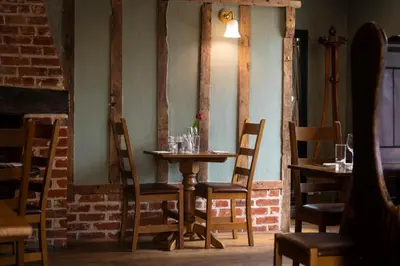 a table and chairs in a room with a brick wall at The Red Lion Hinxton in Hinxton