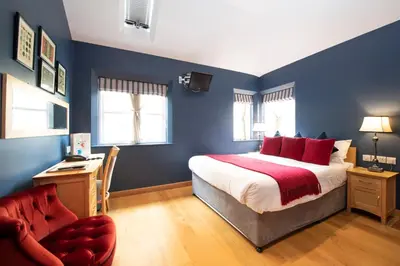 a bedroom with blue walls and a bed with red pillows at The Red Lion Hinxton in Hinxton